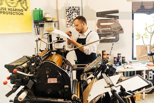 A man with a beard working a large printing machine