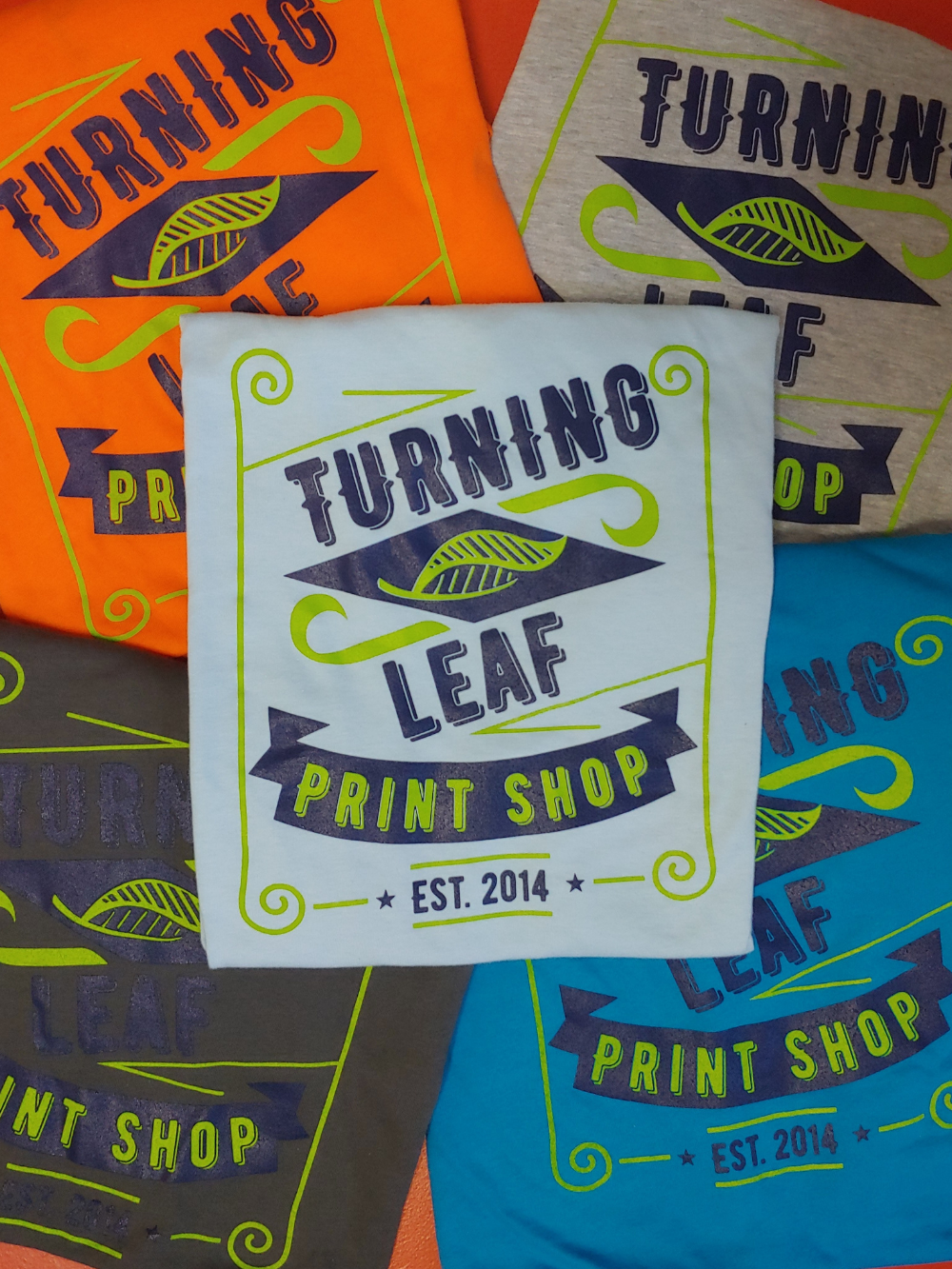 stack of screen-printed t-shirts with Turning Leaf on the front of the shirts