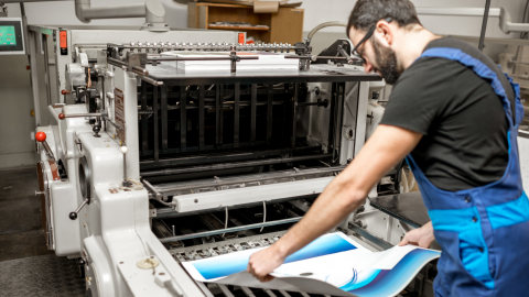 man loading a print into a large format laminator.