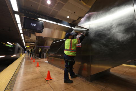 man installing graffiti shield surface protector to the sides of an escalator.